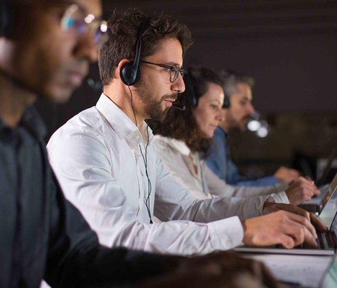 Side view of confident call center operator talking with client Side view of confident call center operator talking with client. Caucasian young man in eyeglasses typing on laptop while serving client. Call center concept